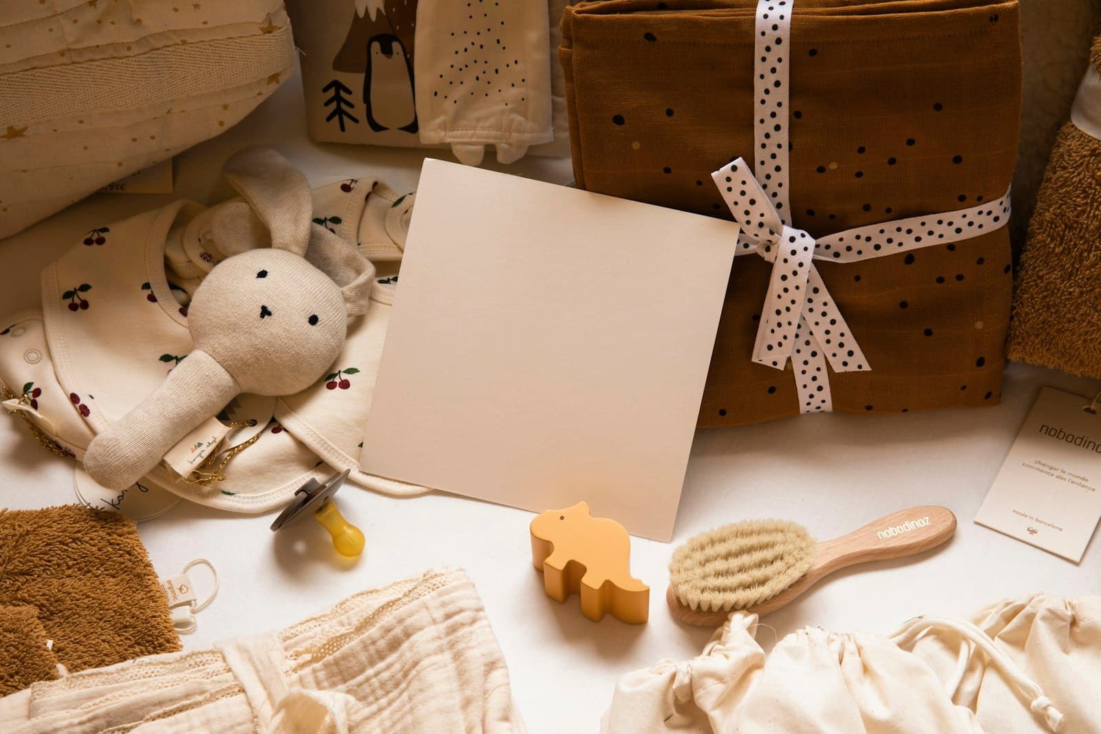 Baby essentials and a wrapped gift laid out — a Hatch Bag on its way to a new mom