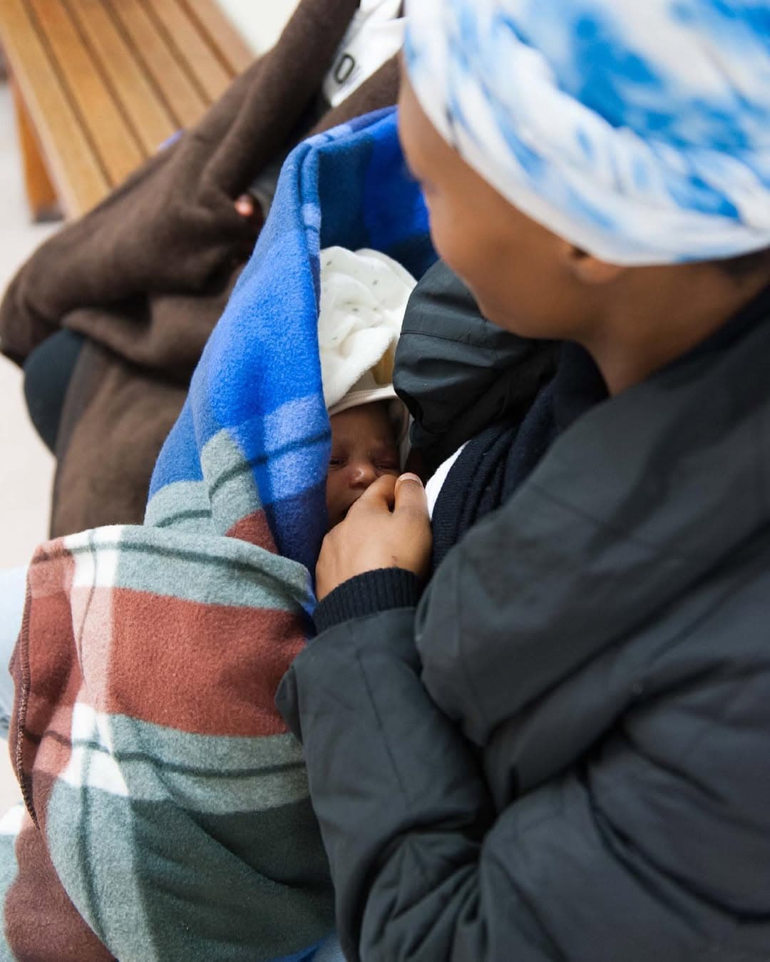 A mom cradling her newborn wrapped in a blanket